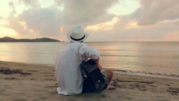 Giovane bellissimo uomo suona la chitarra all'aperto in spiaggia sul mare — Video Stock