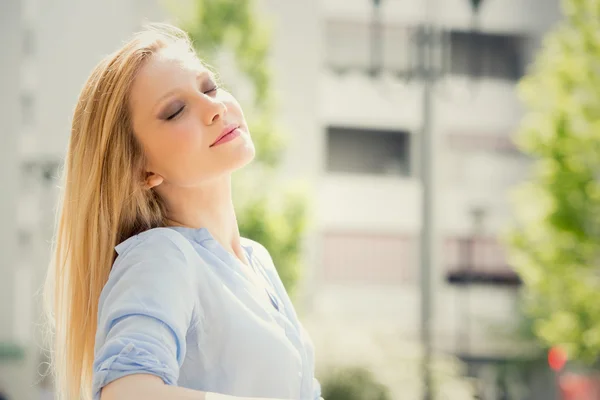 Souriant blonde jeune femme se détendre dans un jardin — Photo