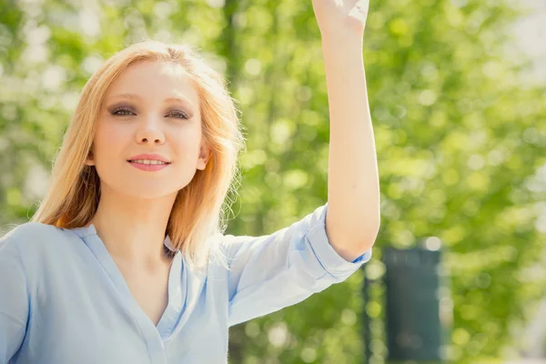 Souriant blonde jeune femme se détendre dans un jardin — Photo