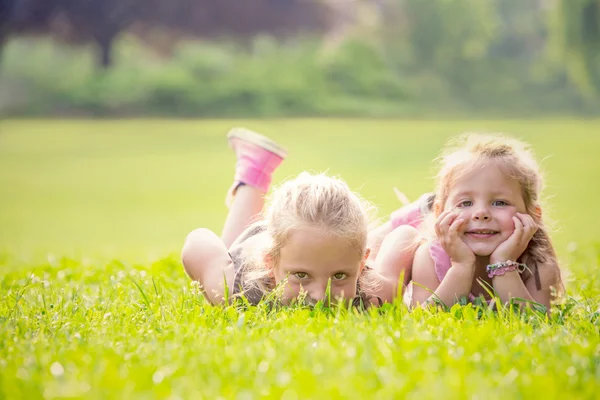 Blonde smiling sister play in a garden — Stock Photo, Image