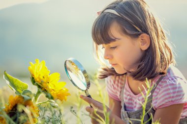 Büyüteç bir bahçe ile oynayan çocuk gülümseyen