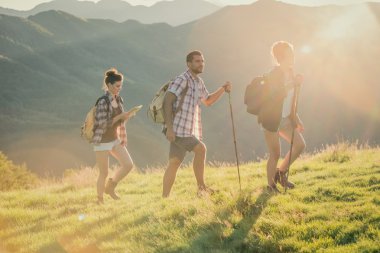 Üç arkadaş dağ yolunda güneşli bir günde yürümek.
