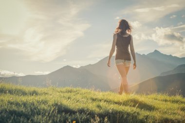 Genç arka kadın güneşli bir günde dağda yürüyüş