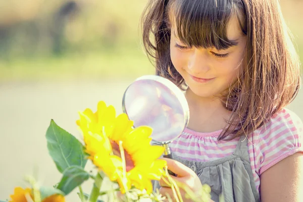 Bambino sorridente che gioca con la lente d'ingrandimento in un giardino — Foto Stock