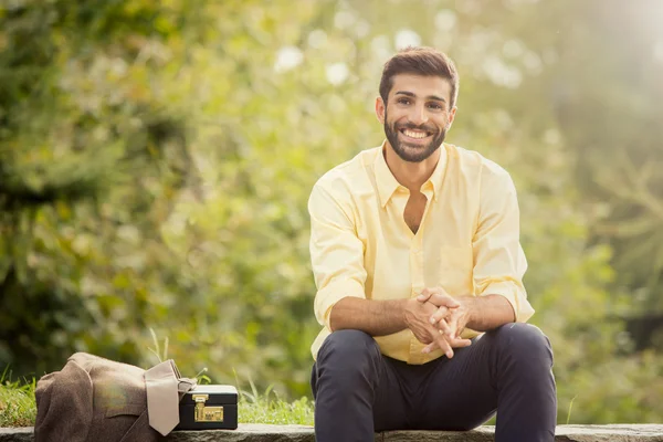 Jonge mooie lachende business man portret buiten in een park — Stockfoto