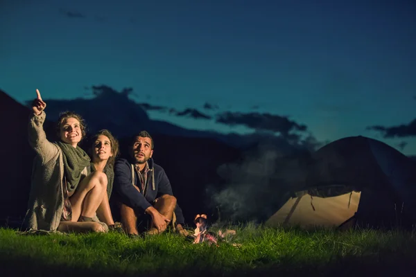 Three friends camping with fire on mountain at sunset — Stock Photo, Image