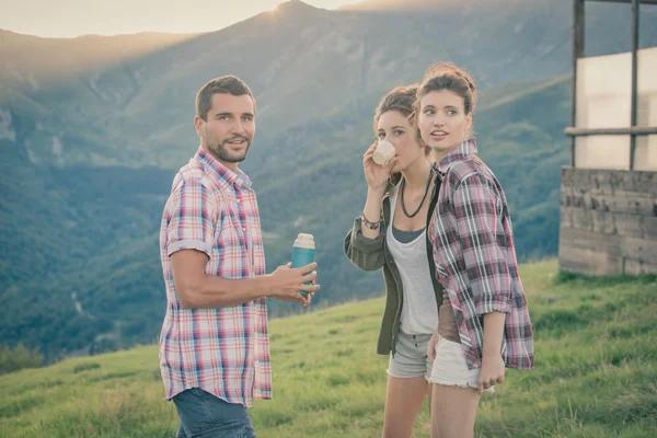 Trois amis se reposent en buvant du thé sur la montagne au coucher du soleil — Photo