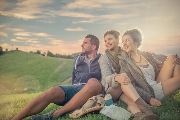 Drie vrienden zitten op gras op berg — Stockfoto