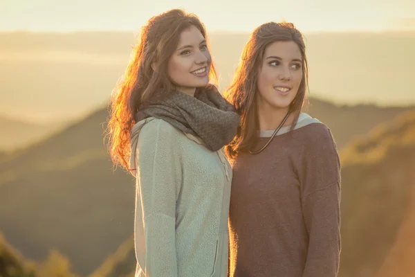 Jovens mulheres sorridentes olhando para o panorama no pôr do sol na natureza — Fotografia de Stock