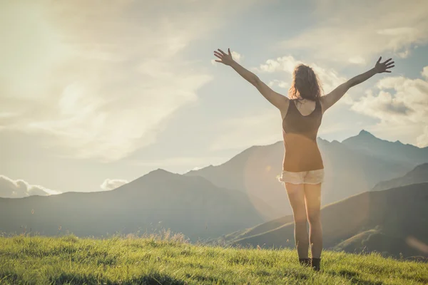 Молода позаду жінка гуляє на горі в сонячний день — стокове фото