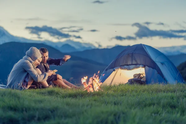 Három barátok, napnyugtakor a tűz, a hegyi camping — Stock Fotó