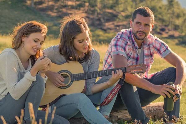 Young woman sing playing guitar with friends on sunset outdoor — Stock Photo, Image