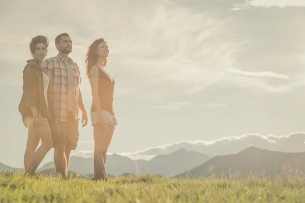 Three friends stand looking at panorama on mountain — Stock Photo, Image