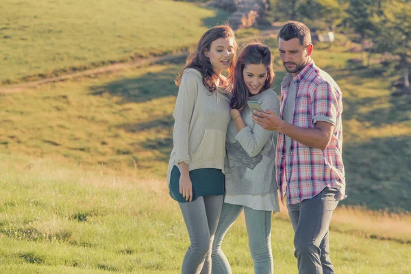 Tres amigos mirando la cámara se abrazan al atardecer al aire libre — Foto de Stock