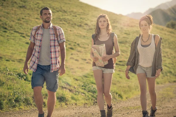 Three friends walk on mountain path in sunny day — Stock Photo, Image