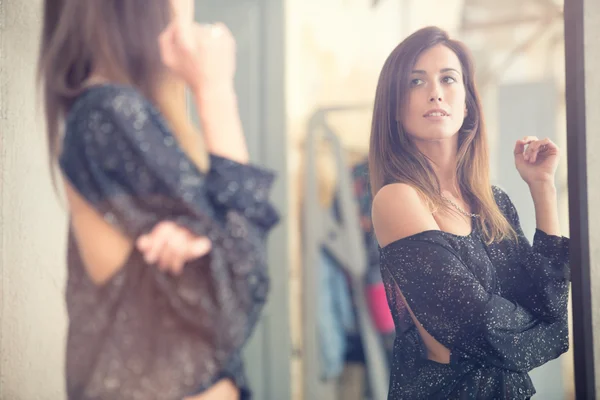 Молода жінка дивиться у дзеркало портрет в магазині — стокове фото