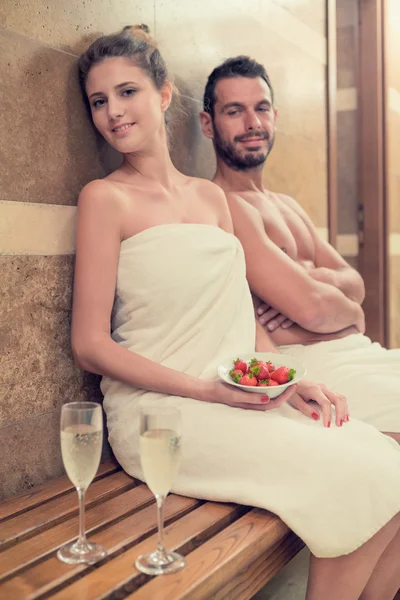 Junges lächelndes Paar entspannt in Badewanne mit Erdbeere und Champagner im Wellnessbereich — Stockfoto