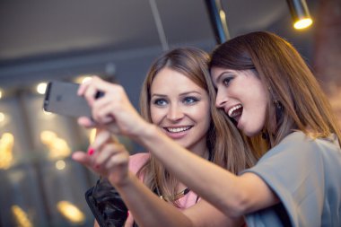 İki gülen arkadaş giyim mağazasında eğleniyor.