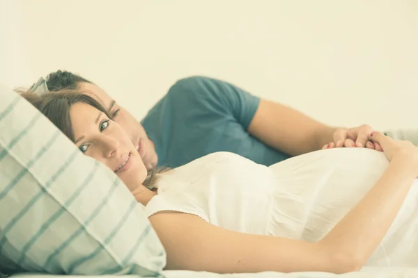 Mãe morena grávida com marido deitado na cama — Fotografia de Stock