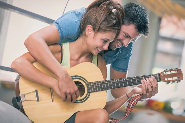 Young couple playing guitar on couch indoor — Stock Photo, Image