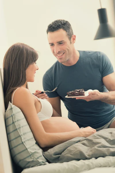 Zwangere brunette moeder met echtgenoot in bed ontbijten — Stockfoto