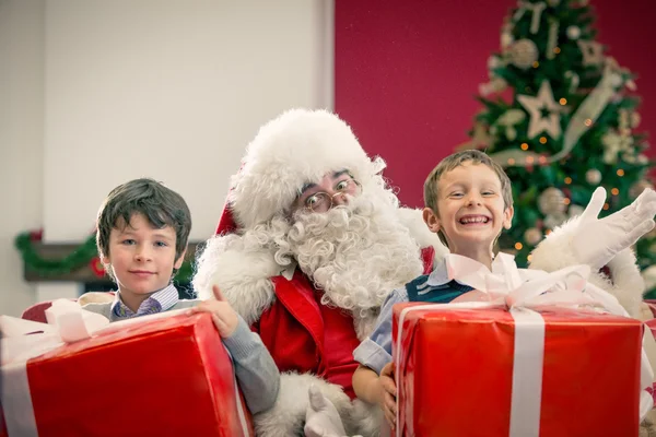 Santa Claus siedzi między chłopców — Zdjęcie stockowe