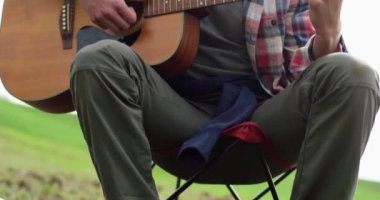 Kamp sırasında gitar çalan erkek ellerini kapat.