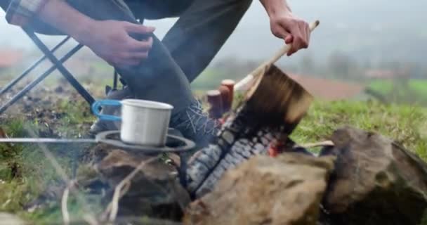 男は食べ物を準備し、キャンプチェアに座っているボン火災の前に。秋の霧の旅でバーベキュー時間. — ストック動画