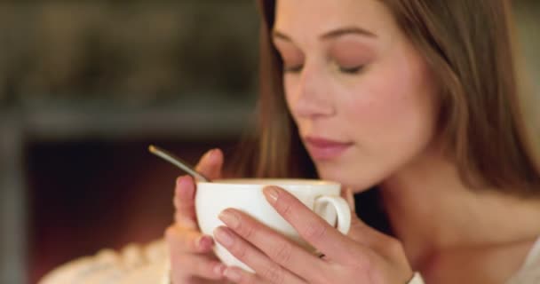 Retrato de perfil de una joven hermosa bebiendo una taza de chocolate en un frío invierno. Mujer relajante mientras bebe bebida caliente en un sofá en casa — Vídeo de stock