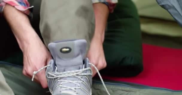 Närbild av ung man binda sina skor efter vandring. Vacker man som kopplar av i ett tält. Campingpassion — Stockvideo