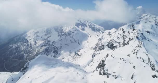 Vista aérea da montanha coberta de neve durante um dia ensolarado no outono. Floresta escura na encosta da montanha. câmara lenta — Vídeo de Stock