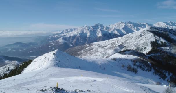 Luftaufnahme einer schneebedeckten Bergkette an einem sonnigen Tag im Winter. Dunkler Wald am Berghang. Zeitlupe — Stockvideo