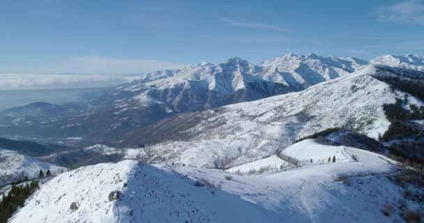 Vista aérea de la cordillera cubierta de nieve durante un día soleado en invierno. Bosque oscuro en la ladera de la montaña. Pureza y ningún concepto de contaminación.cámara lenta — Vídeo de stock