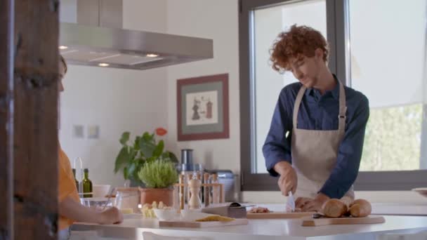 Jongeren koppelen koken en het bereiden van voedsel, spaghetti pasta carbonara maaltijd voor lunch of diner in moderne open ruimte keuken.Moderne liefde relatie, helpen. — Stockvideo