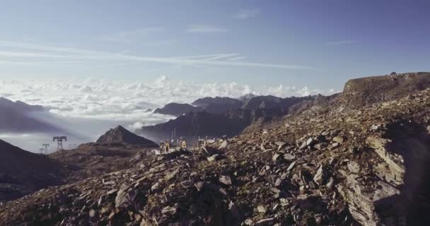 Вид с воздуха на скалистую скалу. Красивый пейзаж на заднем плане, облака покрывают нижнюю горную вершину в солнечный летний день — стоковое видео