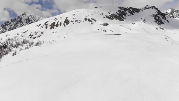 Sobrevoando a montanha coberta de neve. Vista aérea drone de montanha nevada, revelando o grande pico no fundo. Tiro têm nuvens à deriva sutis e sol no fundo. — Vídeo de Stock