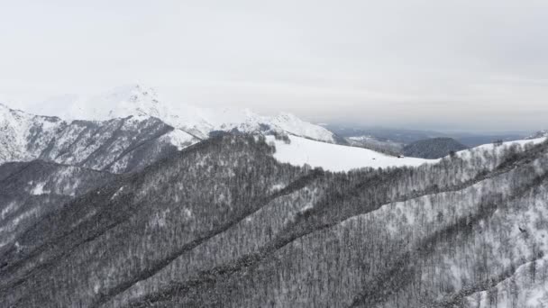 Uitzicht vanuit de lucht besneeuwde bedekte berg. Drone uitzicht op besneeuwde bergketen tijdens een zonnige dag in de winter.Boom donker bos op de berghelling. slow motion — Stockvideo