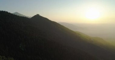 İnsansız hava aracından dağların güzel manzarası. Gün batımında dağların arasındaki ormanların üzerinde dron uçurmak. Dağlardaki güzel güneş ışınları ve ufuktaki gölgeler.