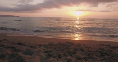 Yaz arkaplanı, güneş kırmızı, turuncu ve sarı bir günbatımında batar. Güneş batıyor, ışık kumda parlıyor..