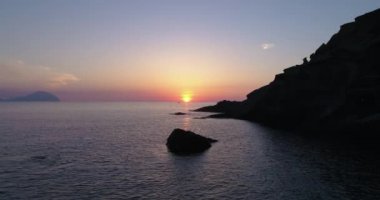 Deniz üzerindeki renkli günbatımının havadan görünüşü, Aeolian adaları. Su yüzeyine yansıyan güneş. Mor, kırmızı, mavi, turuncu alacakaranlık. Yaz günbatımında adaların silueti. Yavaş çekim