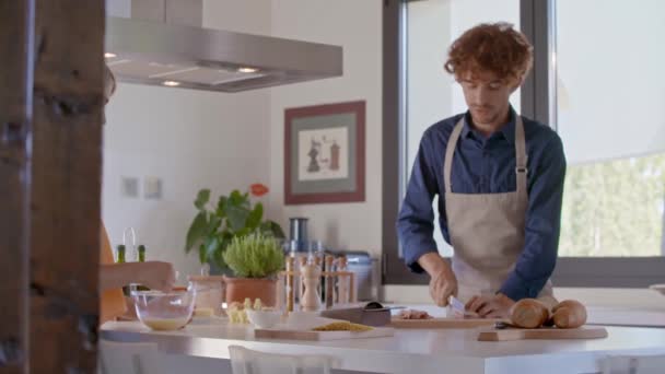 Giovani coppie che cucinano insieme per pranzo. Vita domestica, giovane uomo che parla con la sua ragazza mentre prepara un pasto a casa. rallentatore — Video Stock