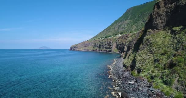 Vista aérea de la costa rocosa de Sicilia en un día soleado. Mar azul, montañas de fondo. Hermosa agua marina mediterránea se encuentra con la costa rocosa. Naturaleza salvaje para los viajeros. — Vídeos de Stock