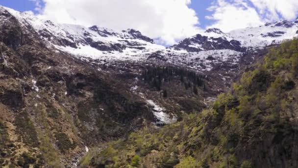 Flygfoto över fjälldalgången under höstsäsongen. Tallskog vilar på bergssluttningen, snötäckta bergskedja i bakgrunden. Blå och molnig himmel. — Stockvideo