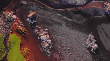 Faroe Adaları 'ndaki kızıl kumsalın havadan görünüşü, yeşil düz araziyi çerçeveleyen insansız hava aracı, kayalık kırmızı plaja taşınıyor ve son olarak yaz günbatımında denize açılıyor..