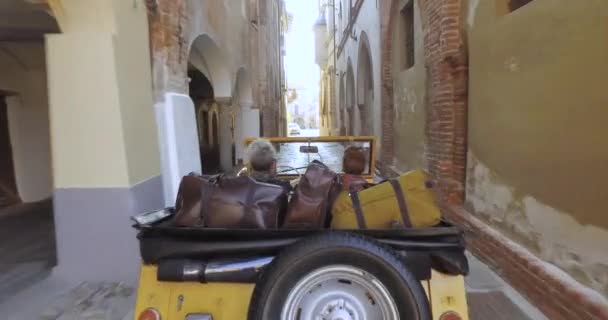 Antena widok z tyłu człowiek jazdy żółty samochód z jego dziewczyna obok niego w charakterystycznym i opuszczonym mieście we Włoszech — Wideo stockowe