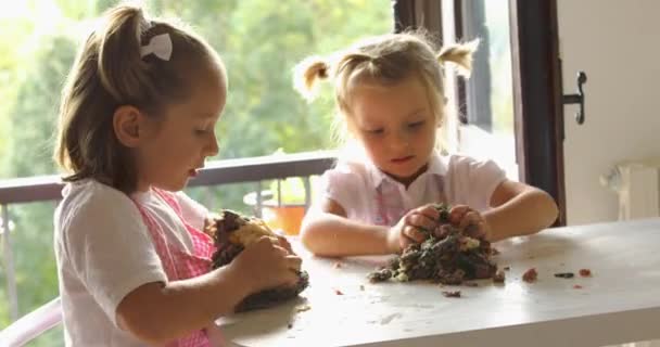 Two beautiful girls cooking cookies during morning light. family cooking, two kids learning by grandma mixing ingredients.Domestic life, family hobbies — Stock Video