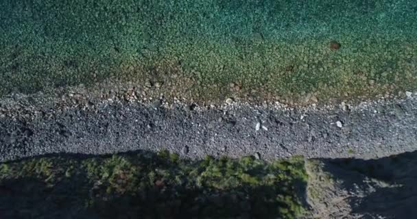 Vista superior del mar, las olas rompen en el alto acantilado de una montaña rocosa y un yate está navegando cerca. Vista aérea de la costa rocosa del mar Mediterráneo en verano, Sicilia. — Vídeos de Stock