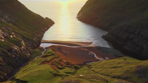 Plajda gün batımının havadan görünüşü. Sakin dalgalarda muhteşem güneş ışığı yansıması. Her iki tarafta da altın plaj ve dağ silueti. Sıradışı manzara ve arka planlar, Faroe adaları. — Stok video
