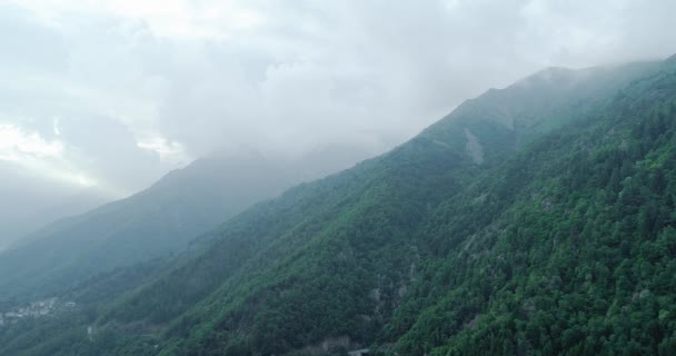 Aérea de volar sobre un hermoso bosque de montaña verde. cordillera brumosa en el fondo. día de verano soleado — Vídeos de Stock