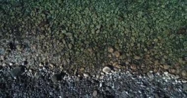 Deniz manzarası, kayalık bir dağın yüksek uçurumunda dalgalar kopuyor ve yakınlarda bir yat yüzüyor. Sicilya 'da yaz mevsiminde Akdeniz' in kayalık kıyı manzarası.